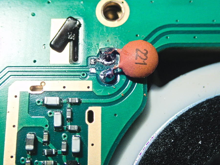 Le condensateur disque 220 pF soudé sur les pattes du micro, à côté du haut-parleur